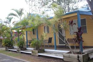 a yellow house with palm trees in front of it at Lani's Holiday Island in Forster
