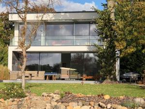 a modern house with glass windows and a yard at Exklusive Seevilla Berlin direkt am Zeuthener See in Berlin