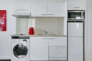 a kitchen with white cabinets and white appliances at Quest South Brisbane in Brisbane