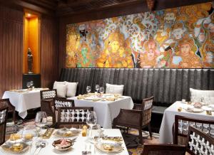 a restaurant with white tables and a large mural at Taj Coromandel in Chennai
