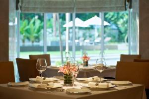 a table with glasses and plates and a flower centerpiece at Taj Coromandel in Chennai