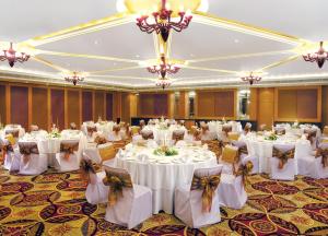 un salón de banquetes con mesas y sillas blancas y lámparas de araña en Taj Chandigarh, en Chandīgarh