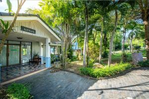 una casa con palmeras delante en Ivy Cottage by Qiu, en Saraburi