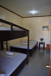 a room with two bunk beds and a table at Bia's Beach House, Pagudpud in Pagudpud