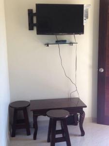 a table with two stools and a television on a wall at Bia's Beach House, Pagudpud in Pagudpud