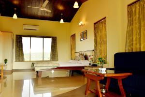 ein Wohnzimmer mit einem Bett und einem Tisch in der Unterkunft The Mango Inn in Dapoli