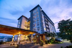 a tall building with tables and chairs in front of it at Clove Hotel Bandung in Bandung