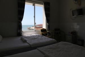 1 dormitorio con 2 camas y una ventana con vistas al océano en Minh Hung Hotel, en Mui Ne