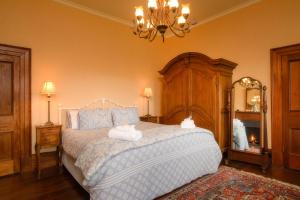 a bedroom with a large bed and a chandelier at Shearers' Quarters Rathmore in Hollow Tree