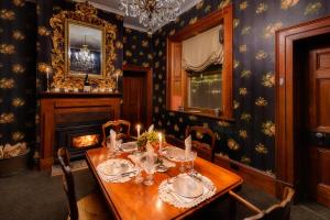 a dining room with a table and a fireplace at Shearers' Quarters Rathmore in Hollow Tree