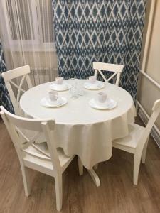 a white table with chairs and cups and saucers on it at TRILLIONER Apartment 885 in Aktau