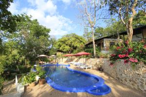 a swimming pool in a yard with chairs and umbrellas at Discovery Island Resort in Coron