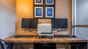 escritorio con 2 monitores de ordenador e impresora en Seven Oaks Hotel Regina en Regina