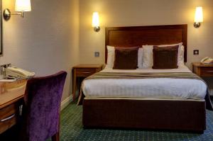 a hotel room with a bed and a telephone at The Bull Hotel; Sure Hotel Collection by Best Western in Peterborough +70 photos