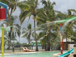 una piscina con palmeras y un parque infantil en Bowen Holiday Park, en Bowen