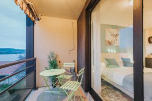 a bedroom with a balcony with a bed and a table at Le Charme des 2 Lacs in Malbuisson
