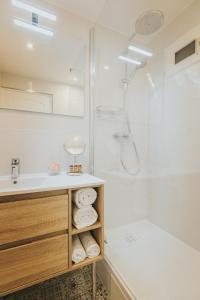 La salle de bains blanche est pourvue d'un lavabo et d'une douche. dans l'établissement Le Charme des 2 Lacs, à Malbuisson