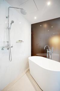 uma casa de banho branca com uma banheira e um chuveiro em Gangneung City Hotel em Gangneung
