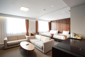 a hotel room with two beds and a living room at Gangneung City Hotel in Gangneung