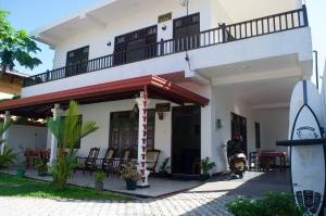 a house with a balcony and a motorcycle parked in front at New Ocean Vibes in Weligama