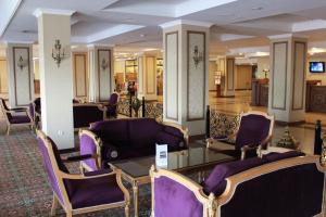 タシュケントにあるグランド ミール ホテルの紫色の椅子とガラスのテーブルが備わるロビー