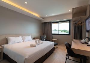 ein Hotelzimmer mit einem Bett und einem Schreibtisch in der Unterkunft The Rich Hotel in Nakhon Ratchasima