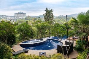a swimming pool in a garden with trees at Clove Hotel Bandung in Bandung