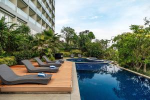 a hotel pool with lounge chairs next to a building at Clove Hotel Bandung in Bandung