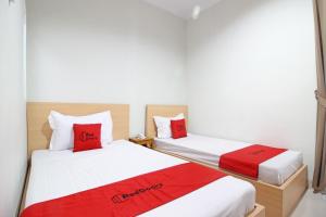 two beds with red pillows in a room at RedDoorz near AMIKOM Yogyakarta in Yogyakarta