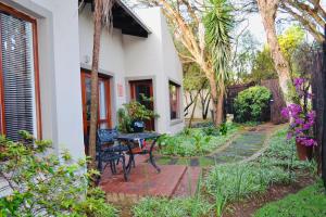 eine Terrasse mit einem Tisch und Stühlen neben einem Haus in der Unterkunft Serendipity Cottage in Johannesburg