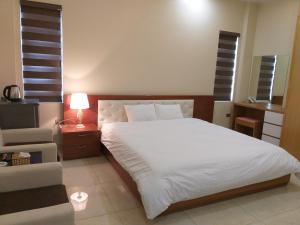 een slaapkamer met een wit bed en een stoel bij Vu Gia Khanh Apartment in Hai Phong