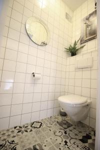 La salle de bains est pourvue de carrelage blanc, de toilettes et d'un miroir. dans l'établissement Apartment Edelweiss, à Zell am See
