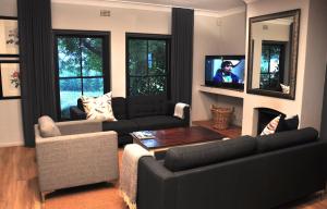 sala de estar con sofá y TV. en Blueberry Hill Cottages en Franschhoek