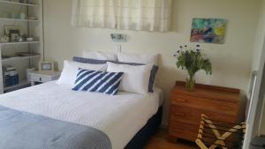 a bedroom with a bed with blue and white pillows at Blooming Delight Tauranga in Tauranga