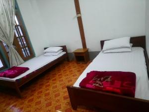 a bedroom with two beds and a red blanket at Diamond Star Guest House in Nyaungshwe Township
