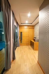 een lege kamer met houten vloeren en gordijnen bij GetZleep PoolVilla in Sattahip