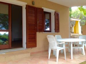 patio con mesa, sillas y ventana en Appartamenti Rena Majore, en Aglientu