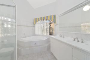 uma casa de banho branca com uma banheira, um lavatório e um espelho. em The Atrium 11 Kentia Close em Port Macquarie