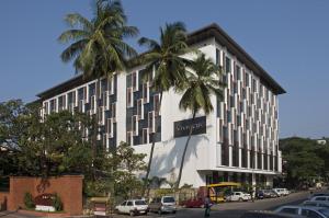 a building with two palm trees in front of it at Vivanta Goa, Panaji in Panaji