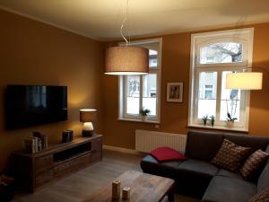 a living room with a couch and a tv and two windows at Apartment Zeitreise in Quedlinburg