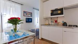ローマにあるColosseo Luxury Apartmentの白いキャビネットと赤い花のテーブル付きのキッチンが備わります。