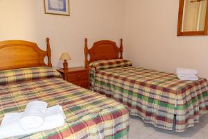 La Playa CaleraにあるApartamento Casanova 1Aのベッドルーム1室(ベッド2台、ランプ、鏡付)