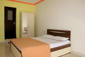 1 dormitorio con 1 cama con sábanas blancas y manta naranja en ALMERIA' Walk to Candolim Beach, en Candolim