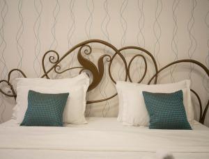 a bed with white pillows and a metal headboard at Garni Hotel DUM in Belgrade
