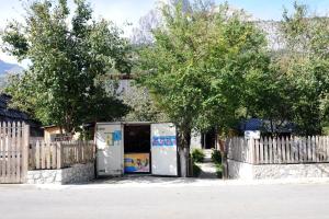 a building with a fence with trees and a refrigerator at Guesthouse Demushi in Valbonë