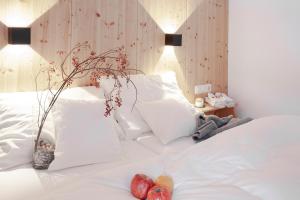 uma cama com almofadas brancas e um vaso com fruta em Apart Korona em Sankt Anton am Arlberg