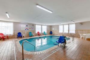 a swimming pool with blue chairs and a table at Quality Suites in Austin