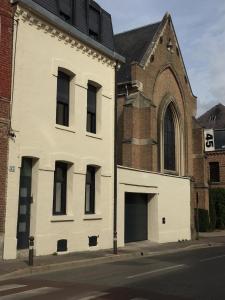 - un bâtiment blanc dans une rue à côté d'une église dans l'établissement Les terrasses de l’orchestre, à Amiens