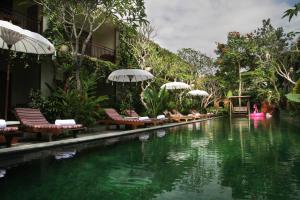 a pool with chairs and umbrellas next to a resort at Sapodilla Ubud in Ubud