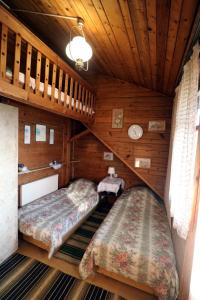 two beds in a room with wooden walls at EkoPens in Radziszów